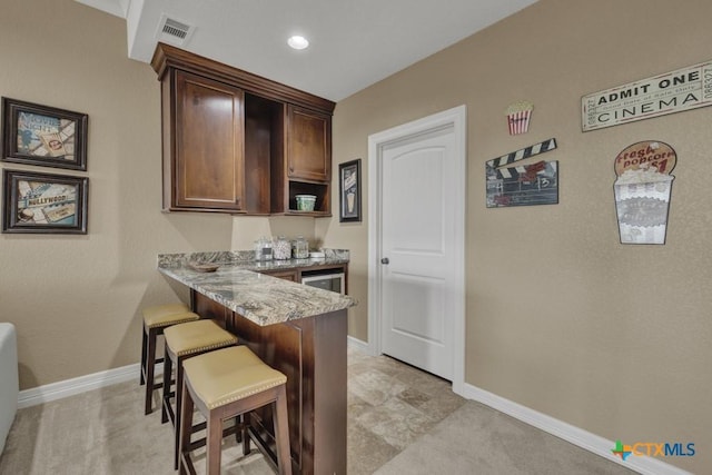 1746 Stagecoach Dr, Canyon Lake, TX 78133 - kitchen featuring a kitchen breakfast bar, light stone countertops, dark brown cabinetry, a peninsula, and light carpet