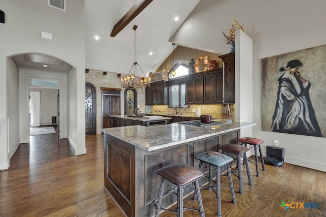 1746 Stagecoach Dr, Canyon Lake, TX 78133 - kitchen featuring arched walkways, dark brown cabinets, stainless steel gas cooktop, dark wood-style flooring, and high vaulted ceiling