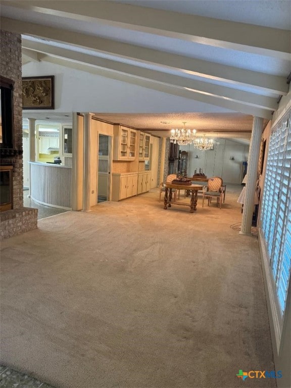 interior space with a brick fireplace, lofted ceiling with beams, a chandelier, and carpet