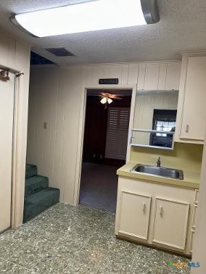 kitchen featuring sink, a textured ceiling, and ceiling fan