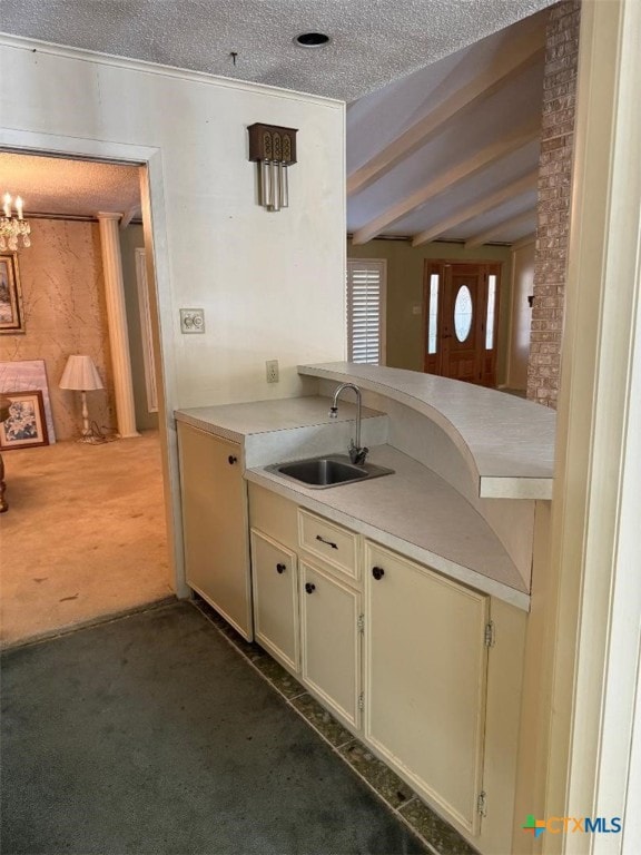 kitchen featuring sink, beam ceiling, a textured ceiling, dark carpet, and a chandelier