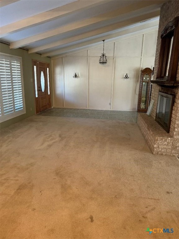 unfurnished living room featuring a brick fireplace, beam ceiling, and carpet flooring