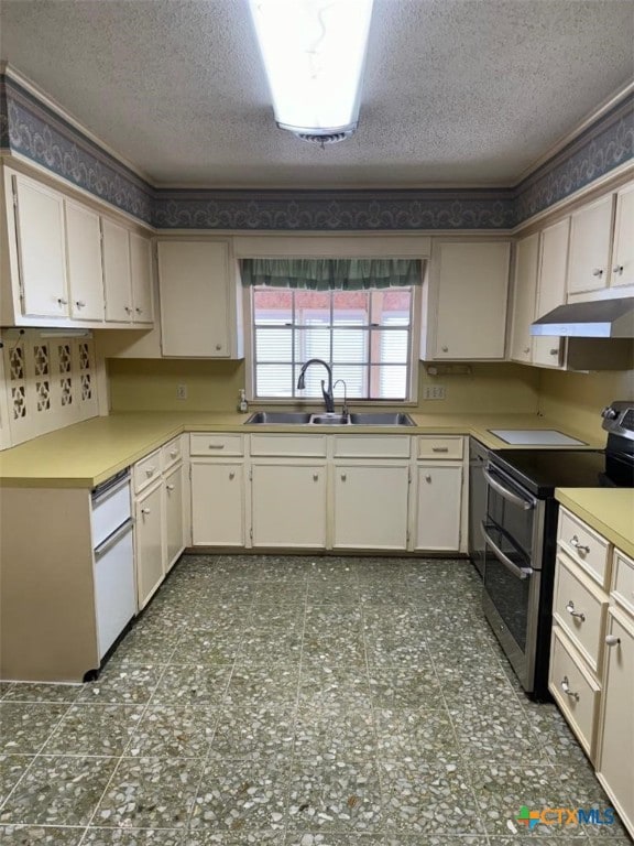 kitchen featuring sink, cream cabinetry, a textured ceiling, and range with two ovens