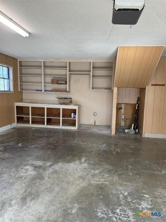 garage featuring a garage door opener and wooden walls