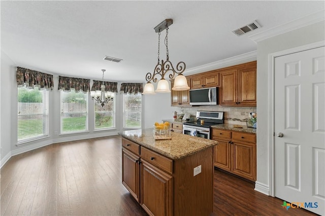 1711 Kelly Ct, New Braunfels, TX 78130 - kitchen featuring appliances with stainless steel finishes, brown cabinets, a chandelier, a center island, and light stone countertops