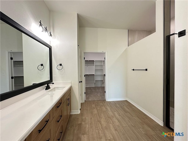 505 Magnolia Dr, Troy, TX 76571 - bathroom with a walk in closet, vanity, wood finished floors, and baseboards