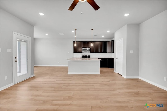 kitchen featuring a kitchen island, decorative light fixtures, ceiling fan, stainless steel appliances, and light hardwood / wood-style flooring