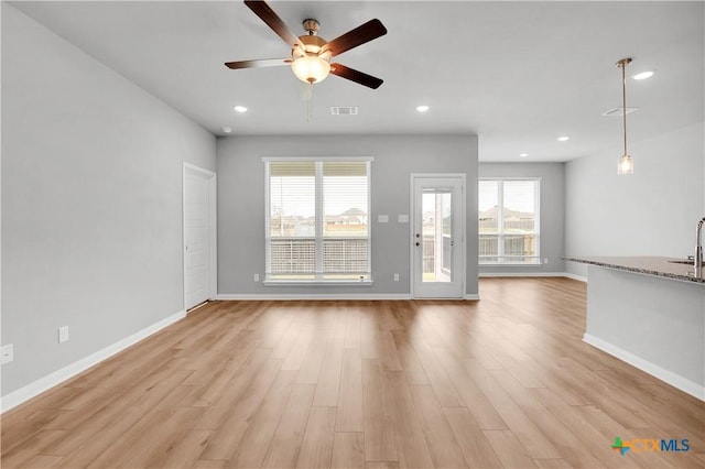 unfurnished living room featuring sink, ceiling fan, and light hardwood / wood-style flooring