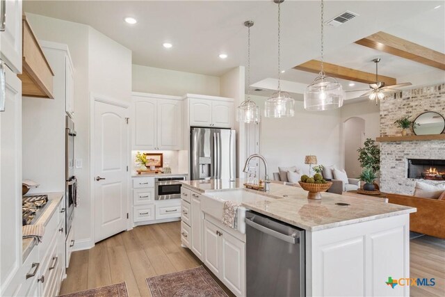 1702 Kellan Dr, Salado, TX 76571 - kitchen with appliances with stainless steel finishes, a sink, light wood-style flooring, open floor plan, and a fireplace
