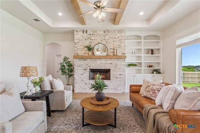 1702 Kellan Dr, Salado, TX 76571 - living area with ceiling fan, wood finished floors, arched walkways, a brick fireplace, and beam ceiling