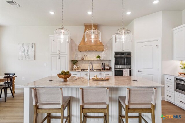 1702 Kellan Dr, Salado, TX 76571 - kitchen with stainless steel appliances, decorative backsplash, a breakfast bar, light wood finished floors, and recessed lighting