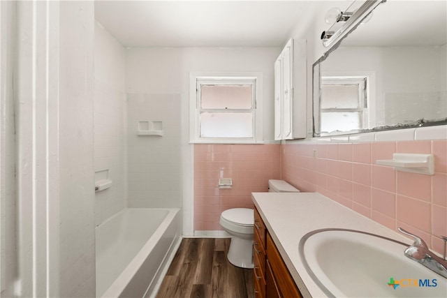 bathroom featuring toilet, vanity, tile walls, and wood-type flooring