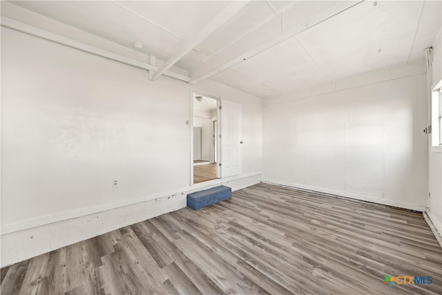 spare room with hardwood / wood-style floors and beam ceiling