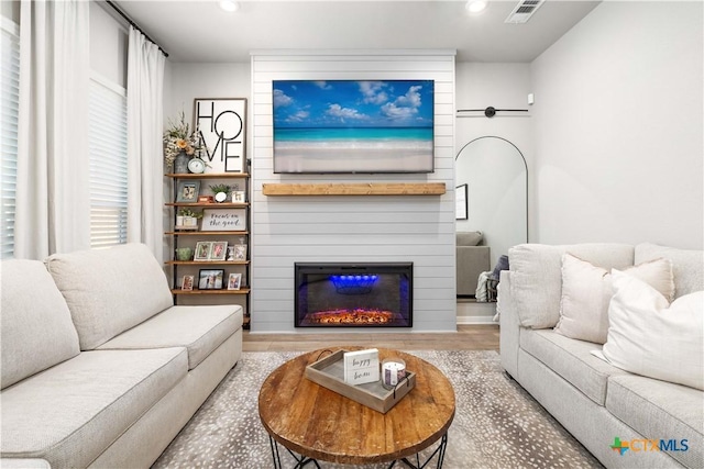 living room featuring hardwood / wood-style flooring and a large fireplace