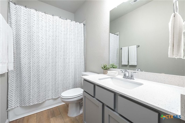 full bathroom featuring hardwood / wood-style flooring, vanity, shower / tub combo, and toilet