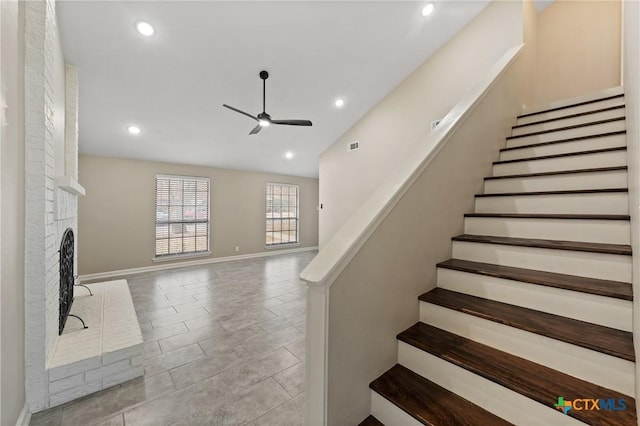 stairway featuring a brick fireplace, vaulted ceiling, and ceiling fan