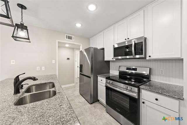 kitchen featuring stainless steel appliances, stone countertops, sink, and white cabinets