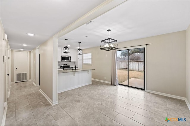 kitchen with light stone counters, appliances with stainless steel finishes, a kitchen breakfast bar, pendant lighting, and white cabinets