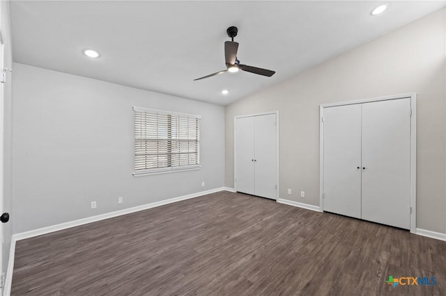 unfurnished bedroom featuring multiple closets, vaulted ceiling, ceiling fan, and dark hardwood / wood-style flooring