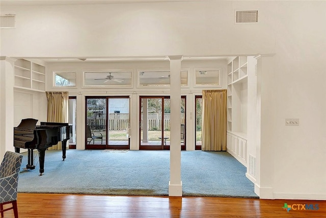 interior space with hardwood / wood-style flooring, ceiling fan, built in shelves, and a high ceiling