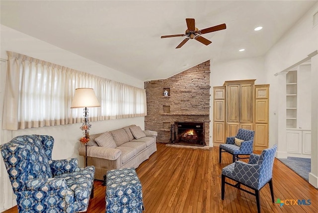 living room featuring ceiling fan, lofted ceiling, hardwood / wood-style floors, and a fireplace