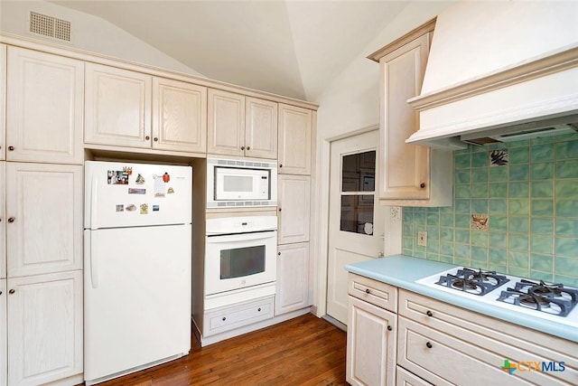 kitchen featuring white appliances, lofted ceiling, custom exhaust hood, and backsplash