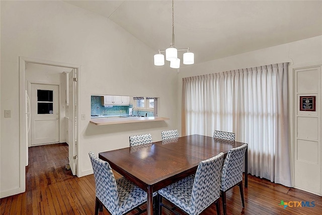 dining area with lofted ceiling, a notable chandelier, and dark wood-type flooring