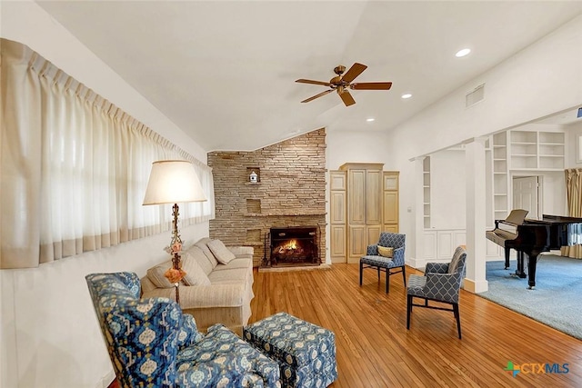 living room featuring light hardwood / wood-style flooring, a fireplace, ceiling fan, and vaulted ceiling