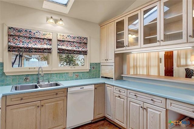 kitchen featuring white dishwasher, a skylight, sink, and decorative backsplash