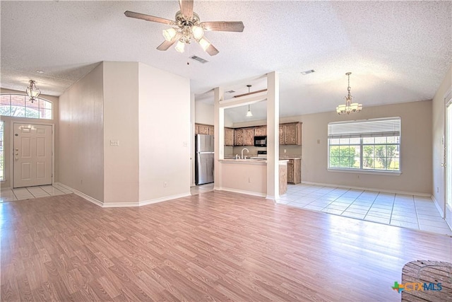 607 Moccasin Dr, Harker Heights, TX 76548 - unfurnished living room with a chandelier, a textured ceiling, light wood-style flooring, and a ceiling fan