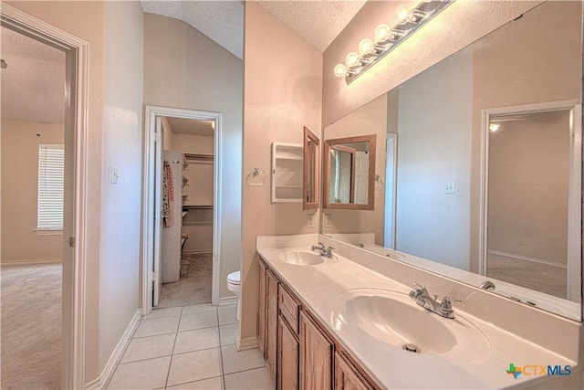 607 Moccasin Dr, Harker Heights, TX 76548 - full bathroom with a textured ceiling, double vanity, vaulted ceiling, tile patterned floors, and a spacious closet