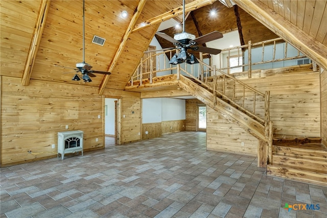 unfurnished living room featuring wood ceiling, wooden walls, ceiling fan, and a wood stove