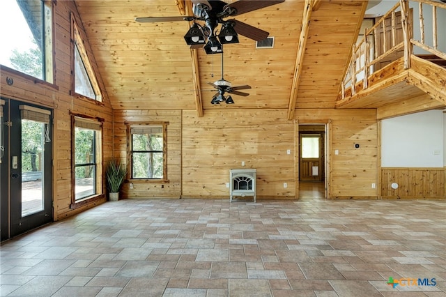 unfurnished living room featuring high vaulted ceiling, wooden walls, a wood stove, ceiling fan, and wood ceiling