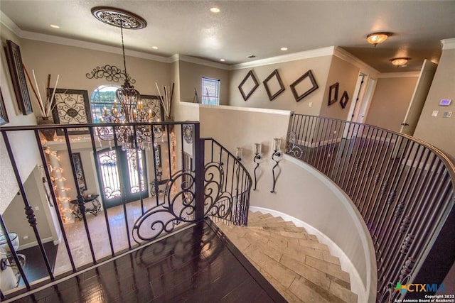 stairs featuring french doors, ornamental molding, and an inviting chandelier