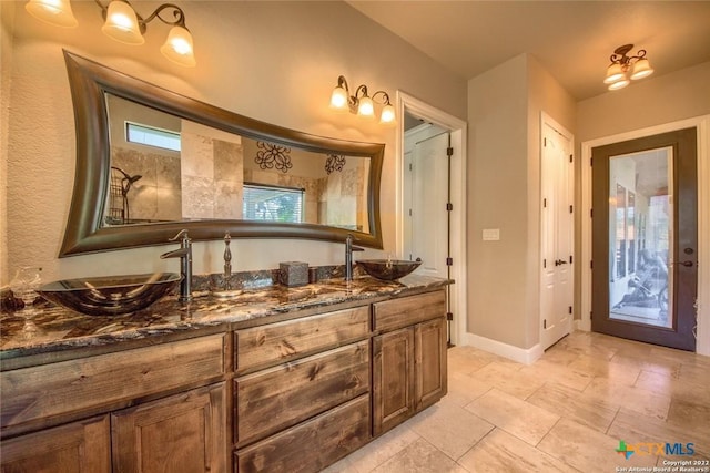 bathroom with double vanity, baseboards, and a sink