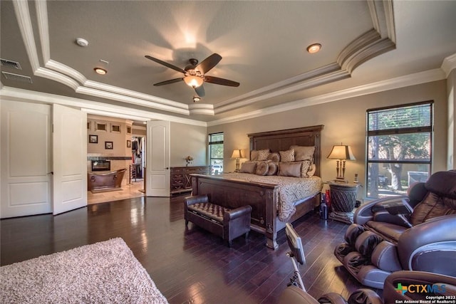 bedroom featuring a wainscoted wall, a tray ceiling, wood finished floors, and multiple windows