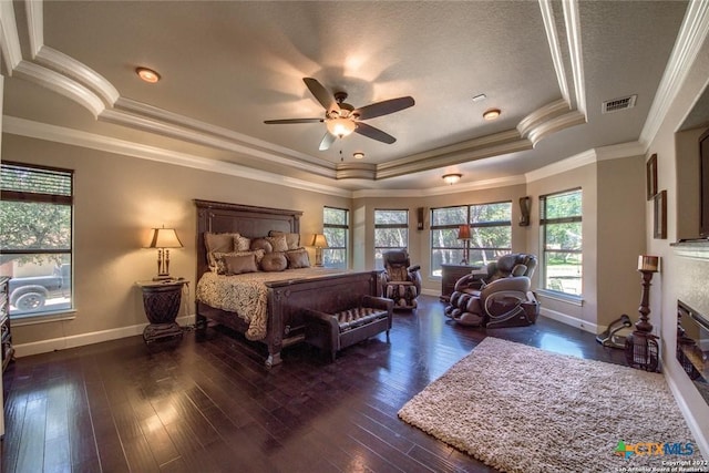 bedroom featuring a tray ceiling, baseboards, visible vents, and dark wood finished floors