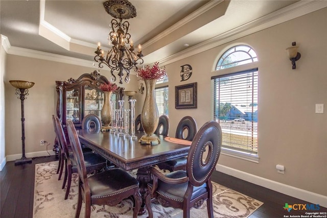 dining room with an inviting chandelier, a raised ceiling, ornamental molding, and wood finished floors