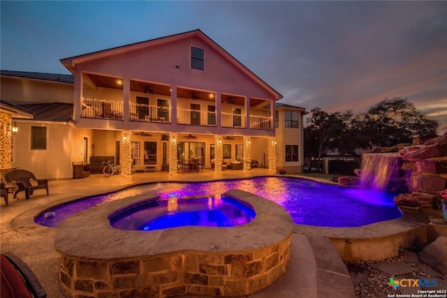 pool at dusk with an outdoor pool, an in ground hot tub, ceiling fan, and a patio area