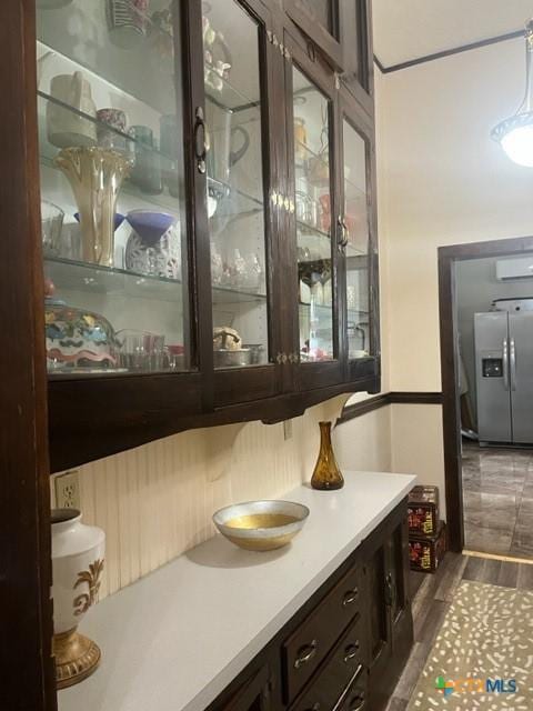 bar featuring dark wood-style floors and stainless steel fridge with ice dispenser