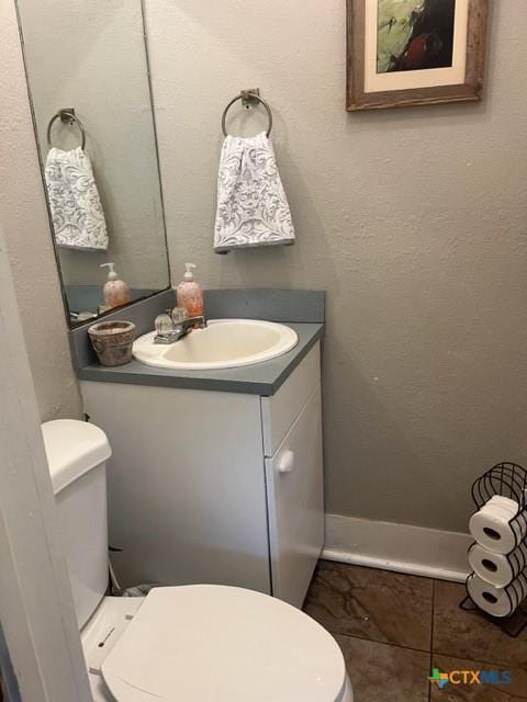 half bathroom with vanity, tile patterned flooring, and toilet