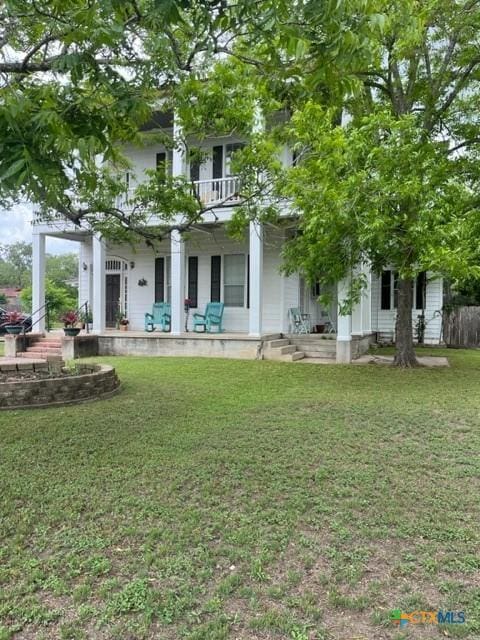 back of house featuring covered porch, a yard, and a balcony