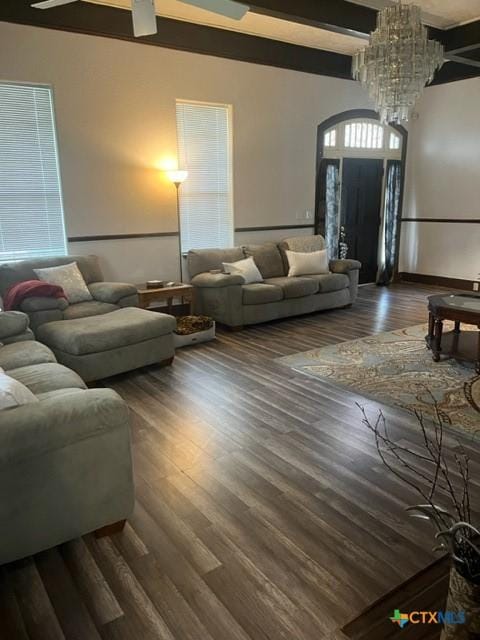 living area with a chandelier, beam ceiling, and wood finished floors