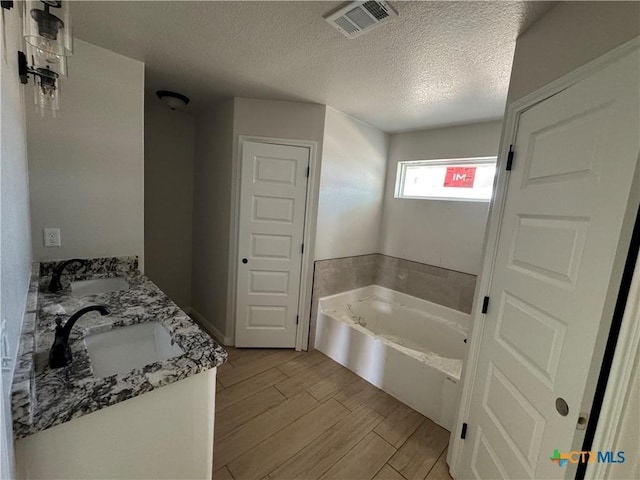 2516 Cowgirl Trl, Belton, TX 76513 - full bathroom with a garden tub, double vanity, a textured ceiling, and wood tiled floors