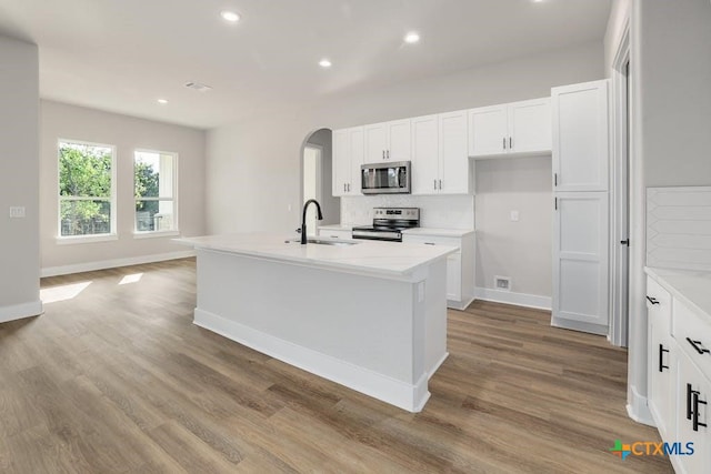 kitchen with light stone counters, sink, a kitchen island with sink, and appliances with stainless steel finishes