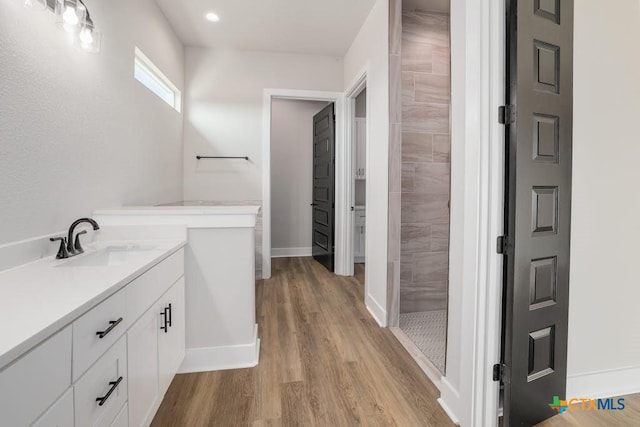 bathroom featuring vanity, wood-type flooring, and tiled shower