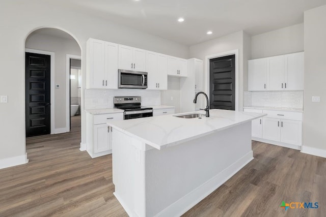 kitchen featuring white cabinets, appliances with stainless steel finishes, sink, and an island with sink