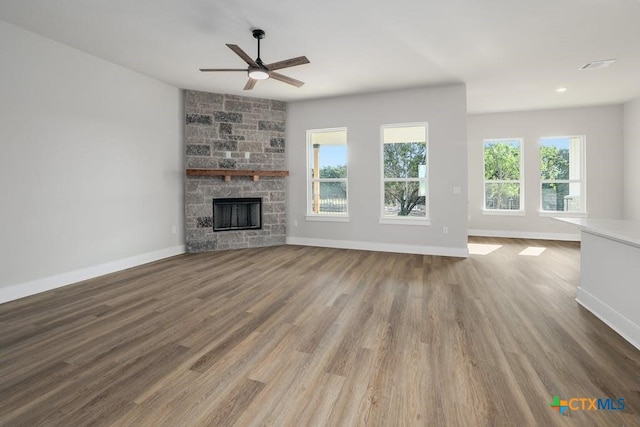 unfurnished living room featuring a stone fireplace, ceiling fan, and hardwood / wood-style flooring