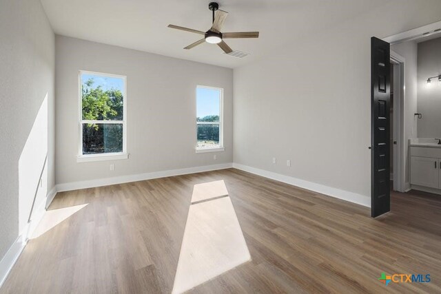 empty room with a wealth of natural light, hardwood / wood-style flooring, and ceiling fan