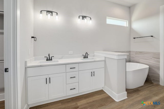 bathroom featuring a washtub, vanity, hardwood / wood-style flooring, and tile walls